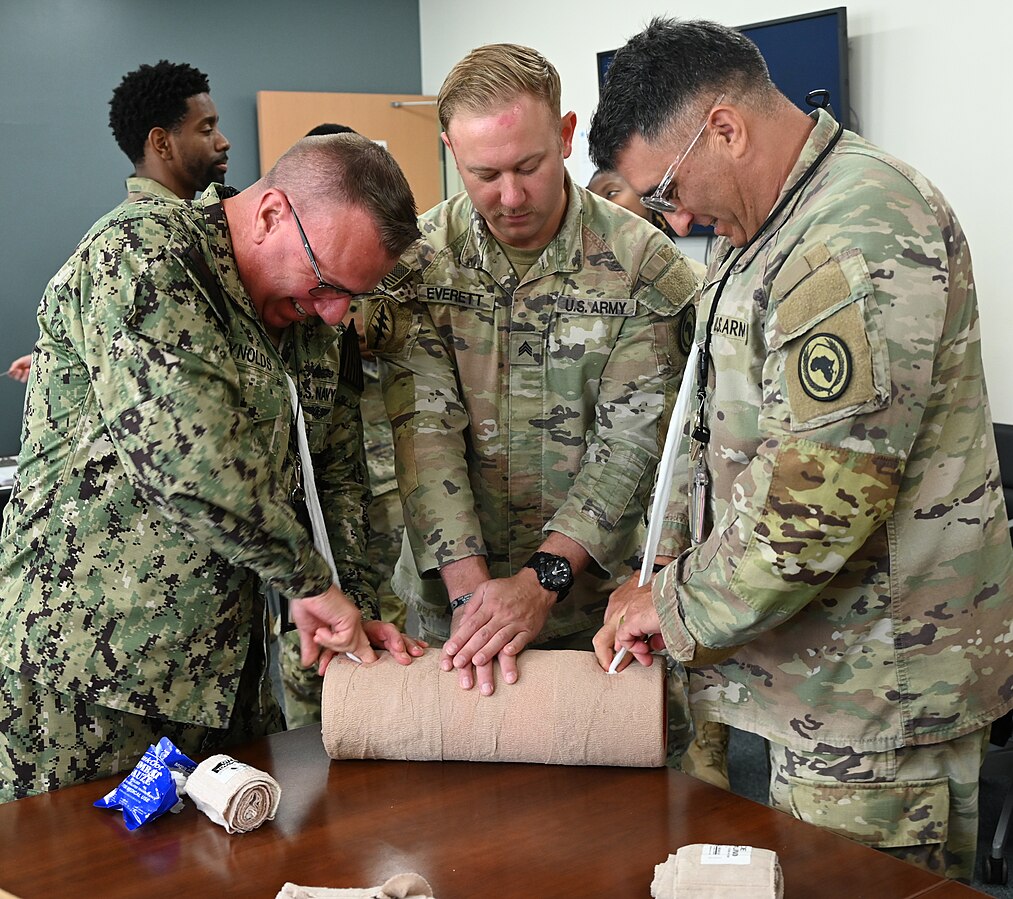 Military personnel are practicing wound packing on a simulated limb