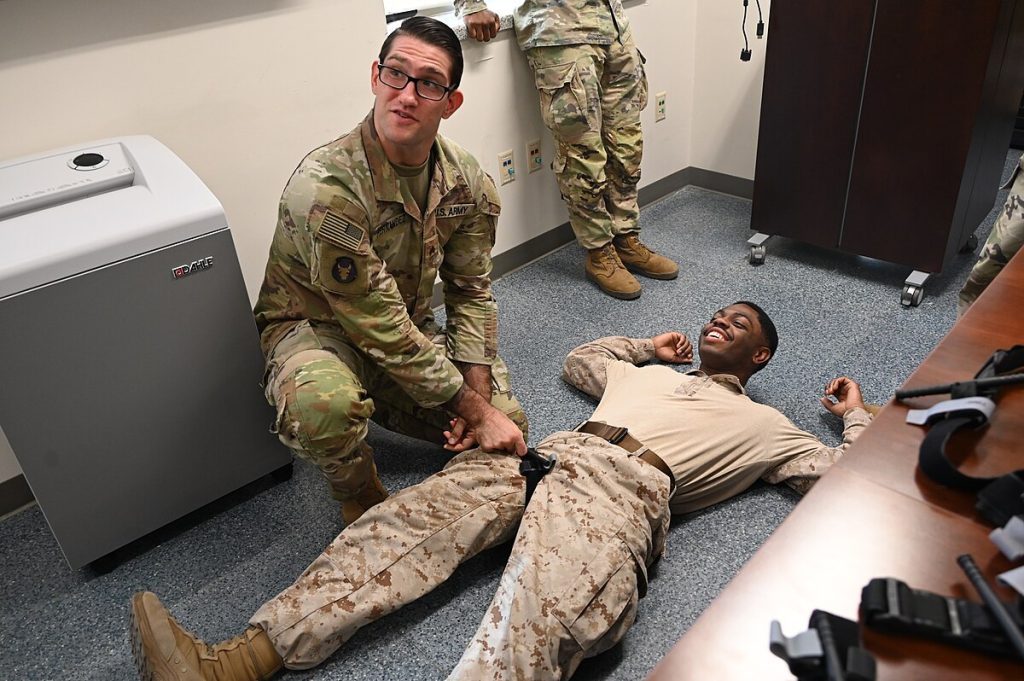 Military personnel are practicing the application of a tourniquet to the upper leg