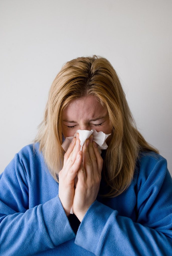 A woman sneezing into a tissue