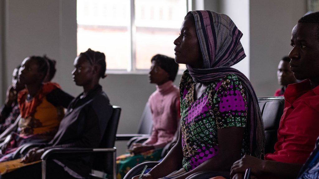 A woman is actively listening, along with others in a dimly lit room